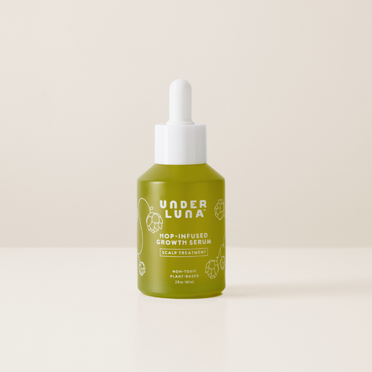 Green bottle of Under Luna hair growth serum on a beige background