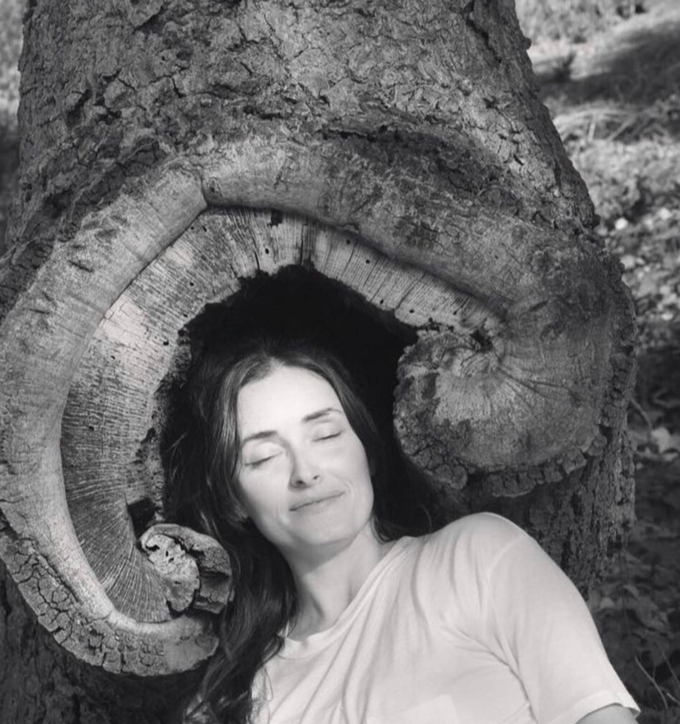 Cortney, founder of wildcare with eyes closed leaning against a large tree trunk