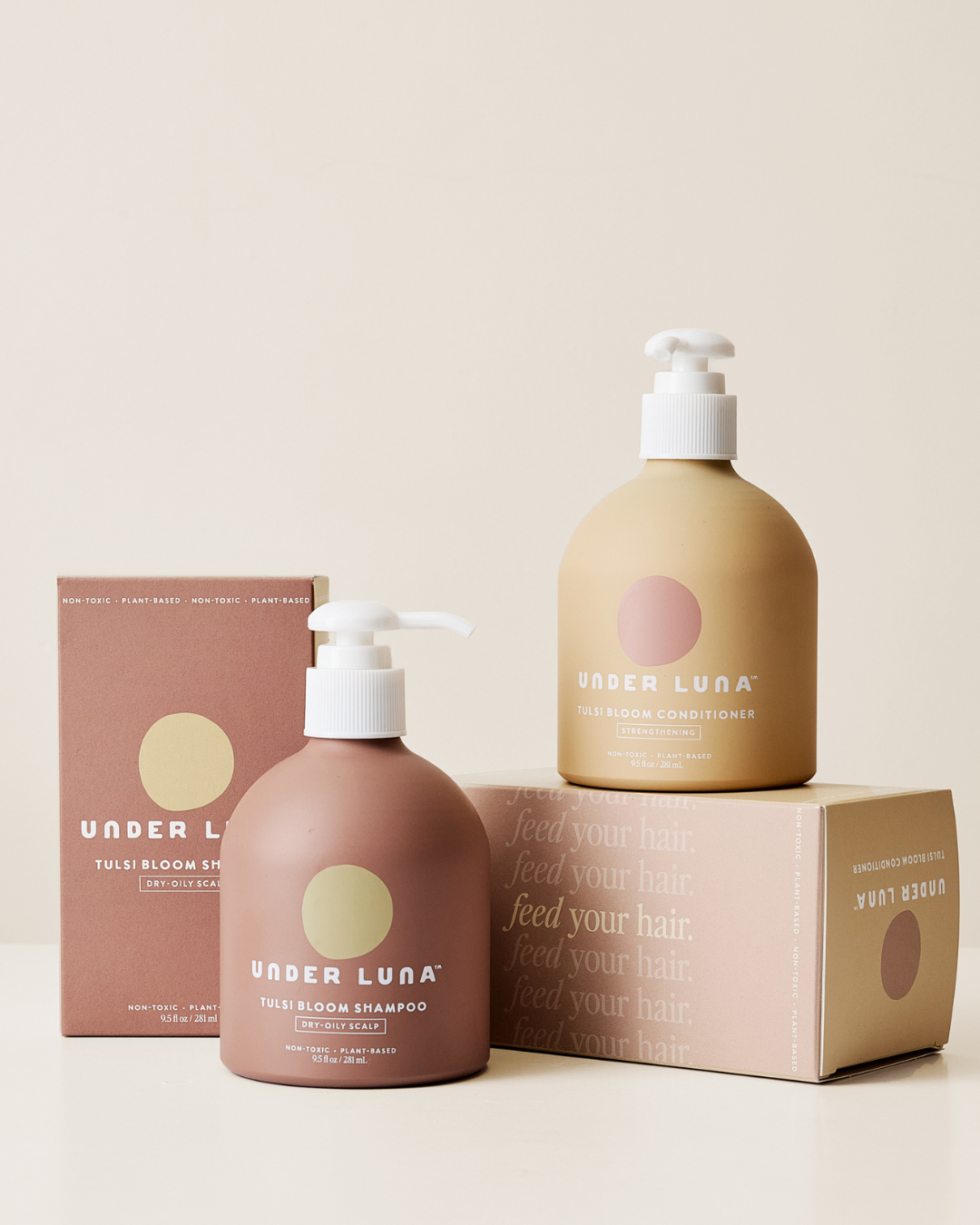 Under Luna shampoo and conditioner bottles with packaging on a beige background